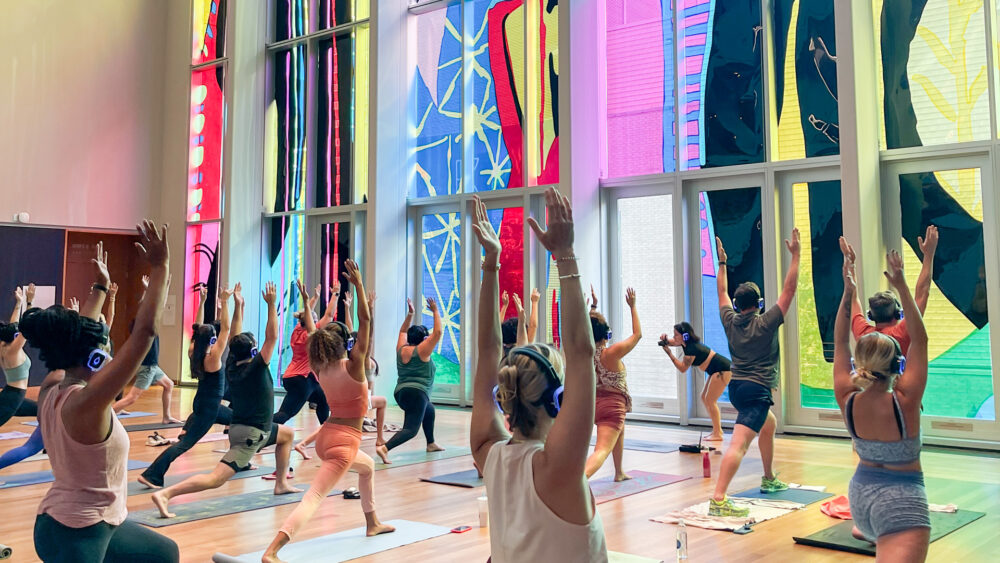 Group of people reaching up during yoga at Mint Museum Uptown