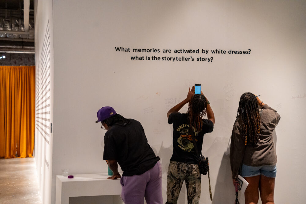 Three people in front of white exhibition wall