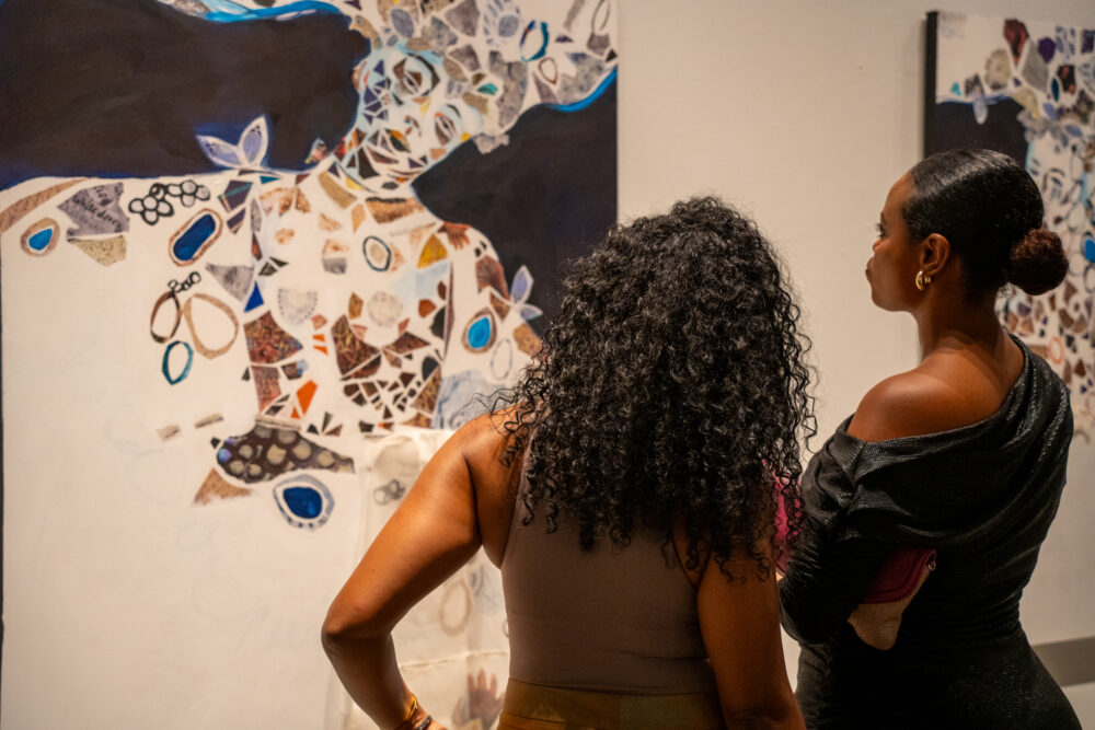 Two people looking at Monique Luck's painting on wall