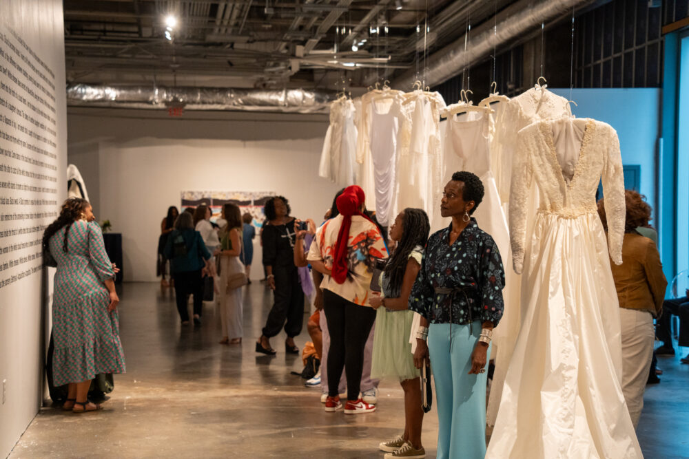 Group of people in Communion of White Dresses gallery space