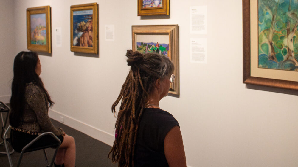 Two people looking at art on the wall during Meditation at the Mint